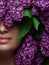 Close-up makeup in pink and purple shades and with flowers around face. Inspiration of spring. Beauty and cosmetics