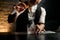 Close-up. Male bartender gently holds in hand tweezers with ice over steaming glass