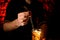 Close-up of male bartender inserts glassy drinking straw into glass with cocktail