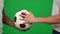 Close-up male Caucasian and African American hands passing football ball on green screen. Unrecognizable sportsmen on