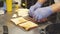 Close up of male chef hands in gloves preparing delicious sandwiches with pastrami meat and cheese in the kitchen