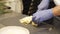 Close up of male chef hands in gloves slicing cheese on board in kitchen