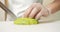 Close up of male chef hands in gloves slicing ripe avocado fruit on white board