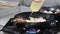 Close-up of a male chef pours oil on a frying pan that stands on the stove in a professional kitchen in a restaurant