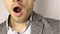 Close-up on male chin with three-day stubble. Tired solid man in grey jacket and white dappled shirt yawns. . no face