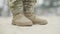 Close-up of male feet in camouflage pants and brown military boots standing on polygon and walking away. Unrecognizable