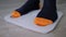Close up: male feet in sock stepping on floor scales - man weighing himself