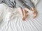 Close up of male and female feet on a bed - Loving couple under grey blanket in the bedroom - Concept of sensual and