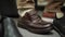 Close-up of male foot with unrecognizable man trying to put on brown boot. Male client trying on too small shoe in store