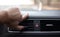 Close-up of male hand adjusting air conditioner button in car.