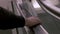 A close-up of a male hand on black rubber handrail of an escalator while moving down.