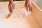 Close up of male hand brooming wooden box with small whisk broom and recycled milk boxes as dustpan