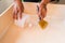 Close up of male hand brooming wooden box with small whisk broom and recycled milk boxes as dustpan