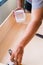 Close up of male hand brooming wooden box with small whisk broom and recycled milk boxes as dustpan