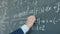 Close-up of male hand with chalk underlining formula on chalkboard in class