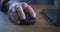 Close up male hand click black computer mouse on work desk. Male working distantly from home with laptop and computer