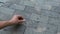 A close-up of a male hand that draws a chalk on the sidewalk.