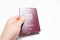 Close-up of male hand holding Moldavian passport of red color, on white.