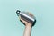 Close-up of male hand holding reusable, aluminum thermo bottle for water, on studio background of cyan, aqua menthe color.