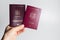 Close-up of male hand holding Romanian and Moldavian passports in hand on white background.