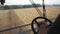 Close up of male hand holding steering wheel and controlling combine during harvest. Unrecognizable farmer working in