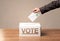 Close up of male hand putting vote into a ballot box