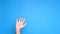 Close up male hand rising on blue background and starts waiving