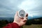 Close-up Male hand and silver compass on a background of mountain landscape. The concept of travel, hiking, help, searching,