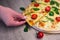 Close up of male hand taking slice of tasty pizza with tomatoes and herbs over wooden table