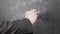 Close-up of male hands in a black suit, the teacher writes math equations
