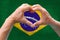 Close-up of male hands in heart form against background of silk national flag of European state of Spain, patriots of country