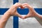 Close-up of male hands in heart form against background of silk national flag of European state of Spain, patriots of country