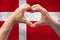 Close-up of male hands in heart form against background of silk national flag of European state of Spain, patriots of country