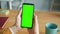 Close-up of male hands holding chroma key green screen smartphone in office