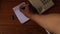 Close up of male hands holding telephone and taking notes in notebook