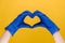 Close up of male hands in medical protection blue gloves making heart symbol as a way to show thank gratitude to doctors