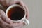 Close-up of male hands and a mug with tea on a beige surface