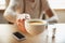 Close up of male hands proposing cup of coffee, sitting at the table with smartphone