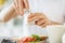 Close up of male hands seasoning food by salt mill