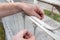 Close-up of male hands of senior man placing plastic cable ties to hold metal mesh on fence