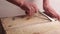 Close-up. Male hands with a wide screwdriver or other mounting tool open a wooden box. Breaking the first plank. Light background.