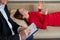 Close-up of a male psychotherapist`s hand writing on a clipboard. A woman in a red dress lies on a couch and talks about