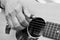 Close up of male`s fingers  placed on soundhole of the acoustic guitar for practicing in playing guitar. Black and white tone