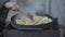 Close-up of male senior Caucasian hand turning potatoes on bbq grill. Unrecognizable old man grilling dinner on