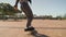 Close up of a male skateboarders feet riding on a skateboard over the pavement in the park