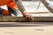 Close up of man builder placing screed rail on the floor covered with sand-cement mix at construction site. Male worker leveling