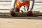 Close up of man builder placing screed rail on the floor covered with sand-cement mix at construction site. Male worker leveling