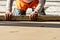 Close up of man builder placing screed rail on the floor covered with sand-cement mix at construction site. Male worker leveling