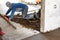 Close up of man builder placing screed rail on the floor covered with sand-cement mix at construction site. Male worker leveling