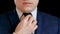 Close-up of a man in a business suit. Businessman, experiencing anxiety and aggression straightens his tie. Style